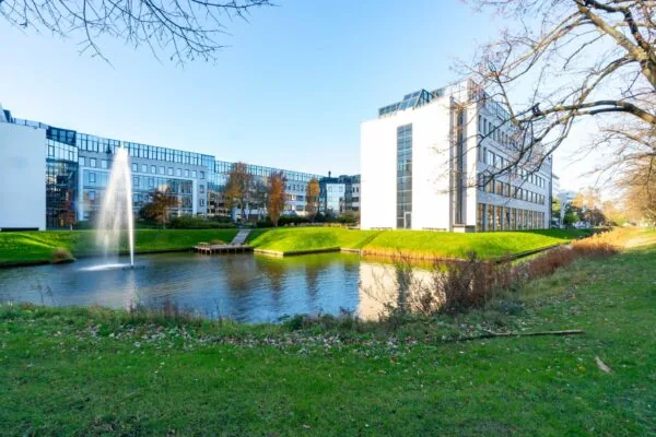 Modern kantoorgebouw aan de De Bruyn Kopsstraat met vijver en fontein op de voorgrond.